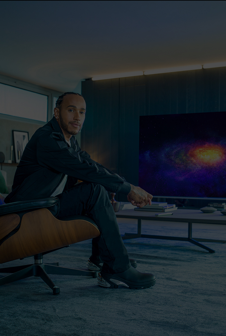 Lewis Hamilton sitting on a couch and behind him is the LG SIGNATURE OLED 8K TV.